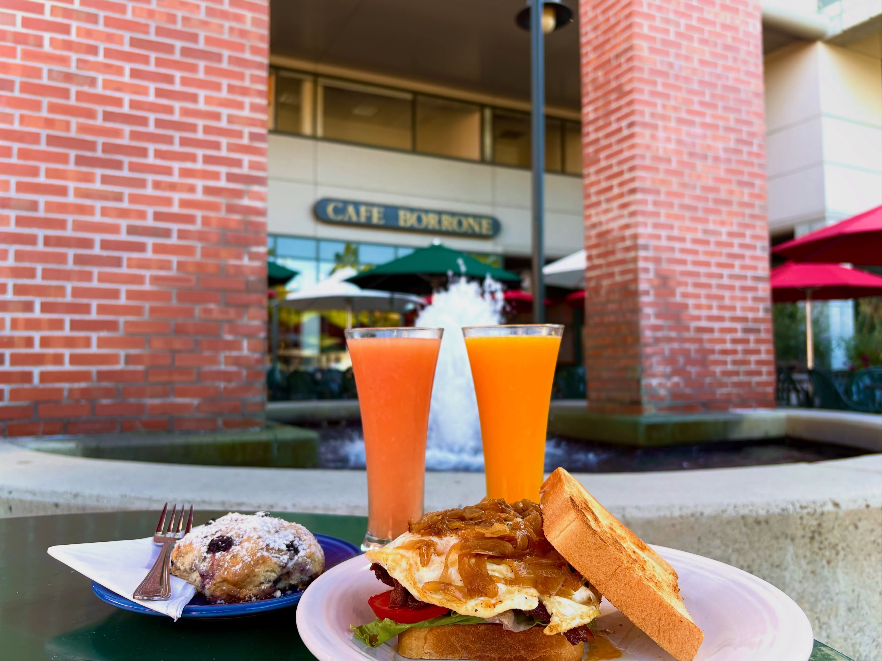Blueberry muffin and breakfast sandwich with fresh juice on the patio