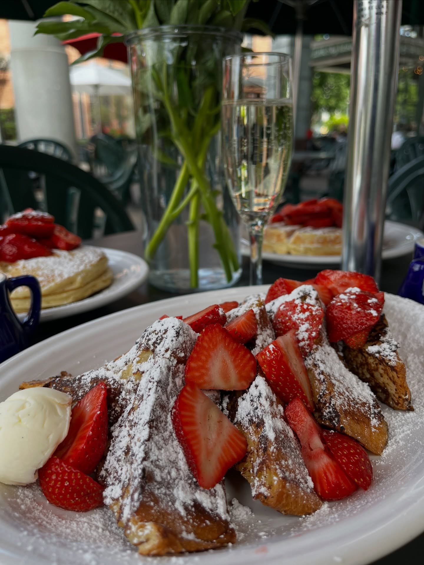 French toast with strawberries and powdered sugar beside fresh peonies